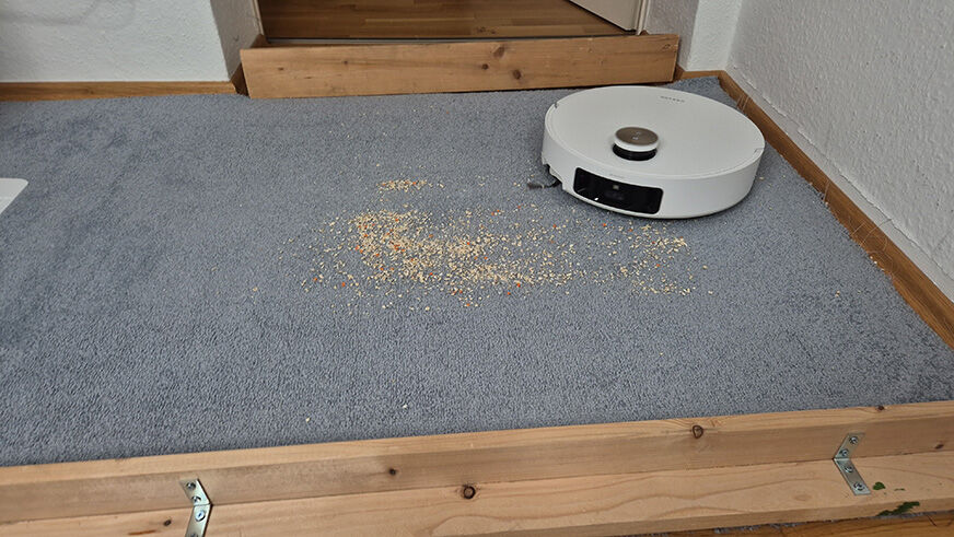 Der Matrix 10 Ultra saugt auf einem Teppich Sand und Linsen.